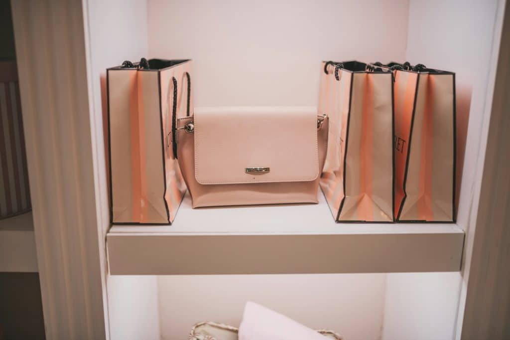 Gorgeous luxury dressing room with pastel puce soft-hued neutral tone brand shopping bags on shelves